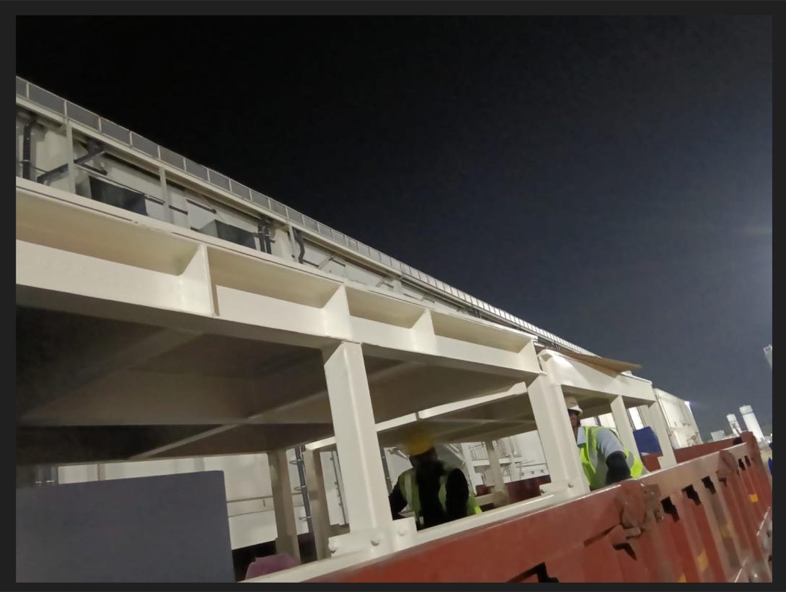 White-painted structural steel platform and walkway erected at night