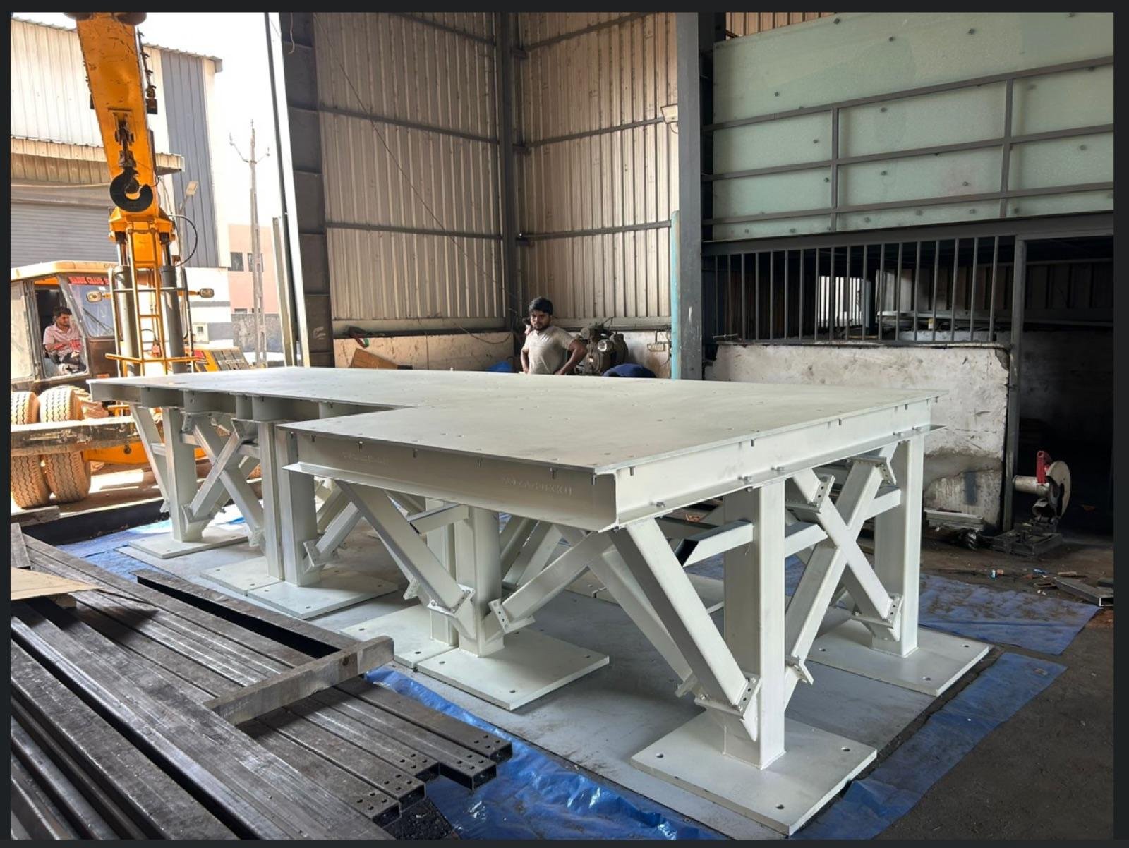Two fabricated steel machine platforms with cross-bracing beside a mobile crane